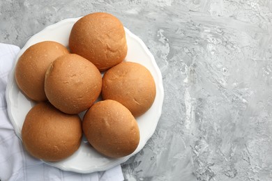 Fresh tasty buns on grey table, top view. Space for text