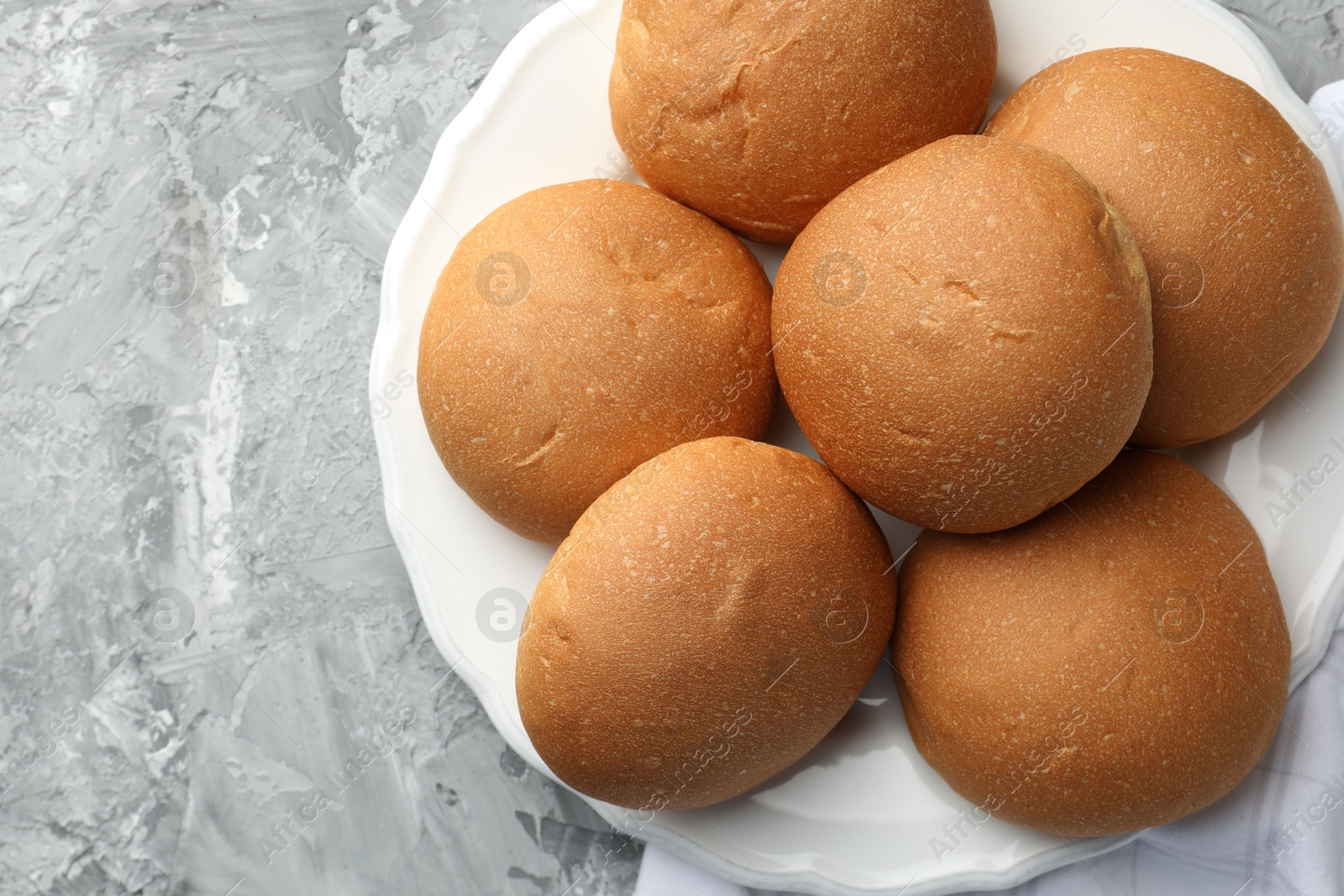 Photo of Fresh tasty buns on grey table, top view