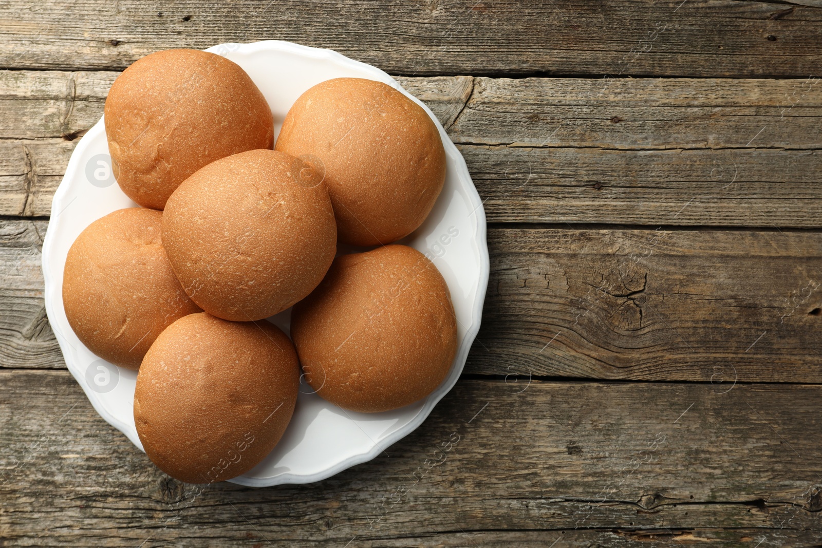 Photo of Fresh tasty buns on wooden table, top view. Space for text