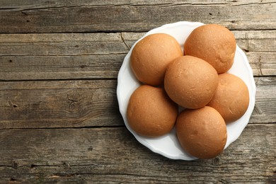 Photo of Fresh tasty buns on wooden table, top view. Space for text