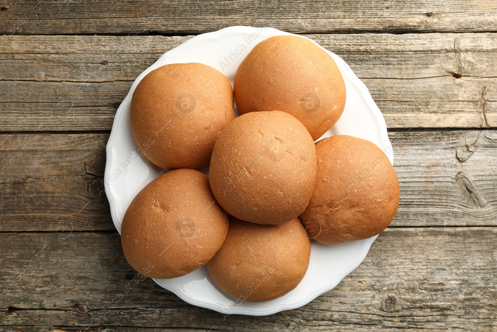 Photo of Fresh tasty buns on wooden table, top view