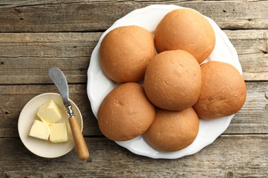 Photo of Fresh tasty buns and butter on wooden table, top view