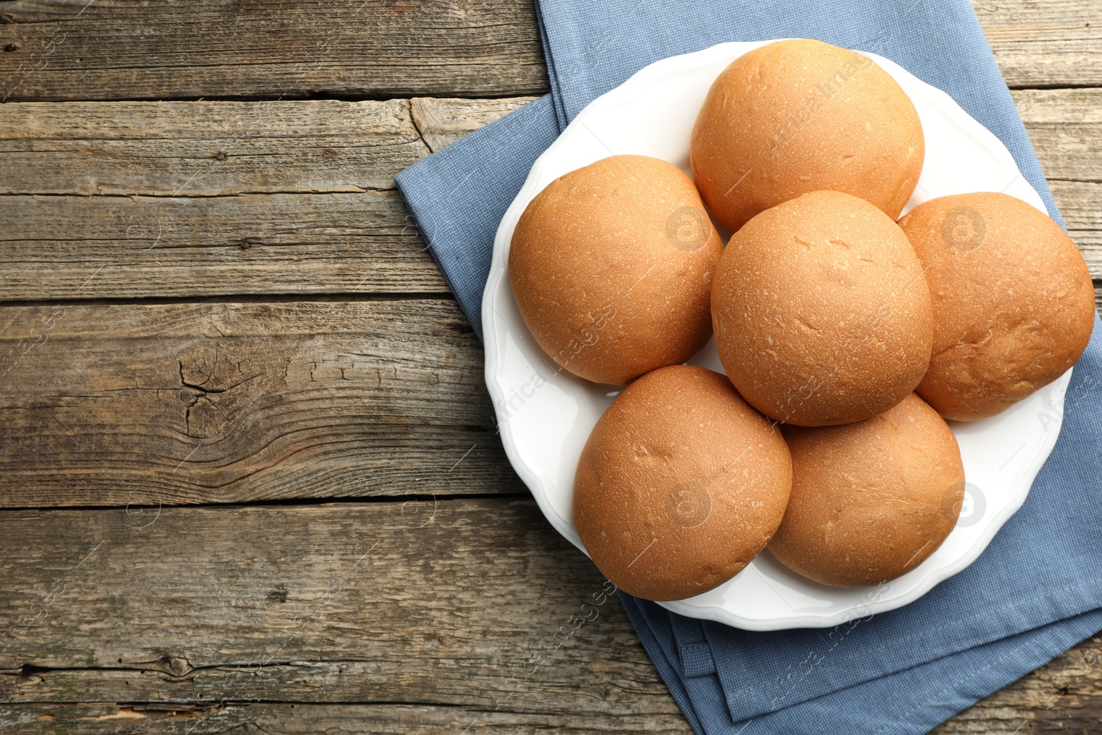 Photo of Fresh tasty buns on wooden table, top view. Space for text