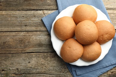 Fresh tasty buns on wooden table, top view. Space for text