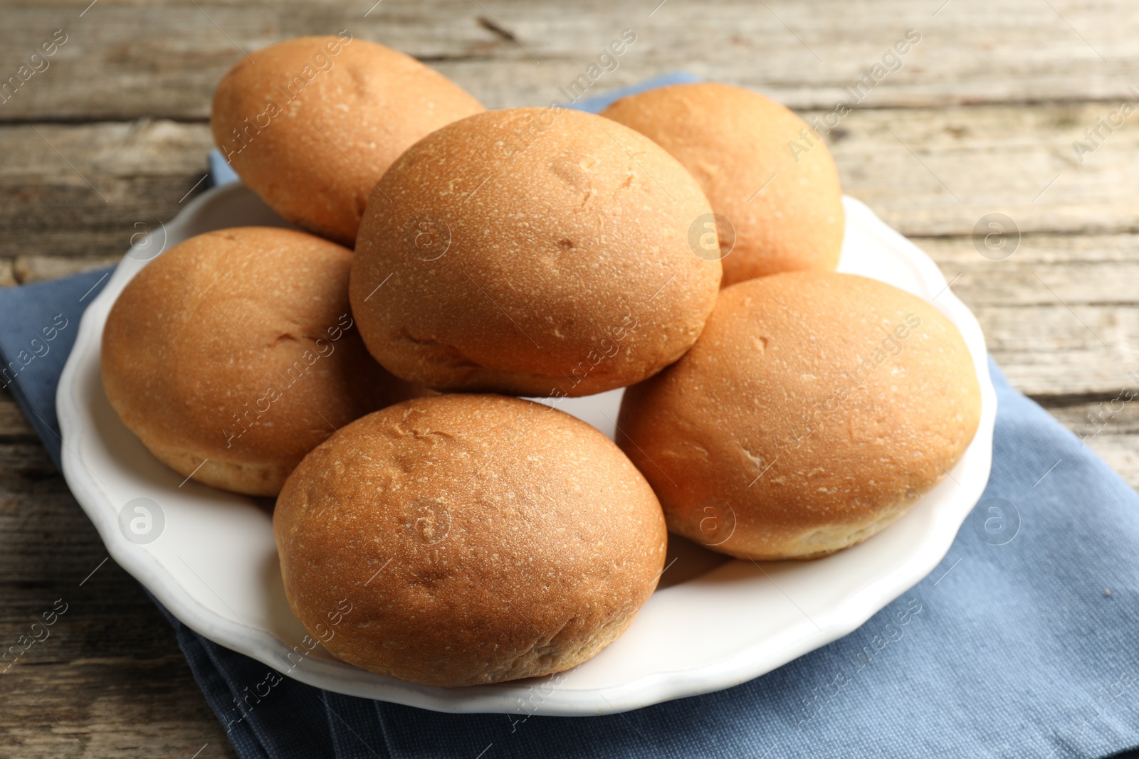 Photo of Fresh tasty buns on wooden table, closeup