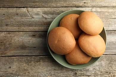 Fresh tasty buns on wooden table, top view. Space for text