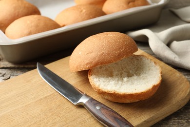 Photo of Fresh tasty buns and knife on table, closeup