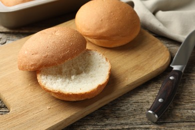 Photo of Fresh tasty buns and knife on wooden table, closeup