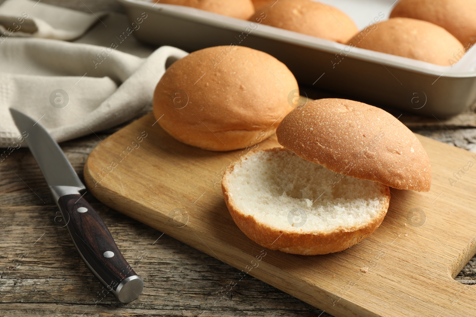 Photo of Fresh tasty buns and knife on wooden table, closeup