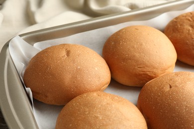 Photo of Fresh tasty buns in baking dish on table, closeup