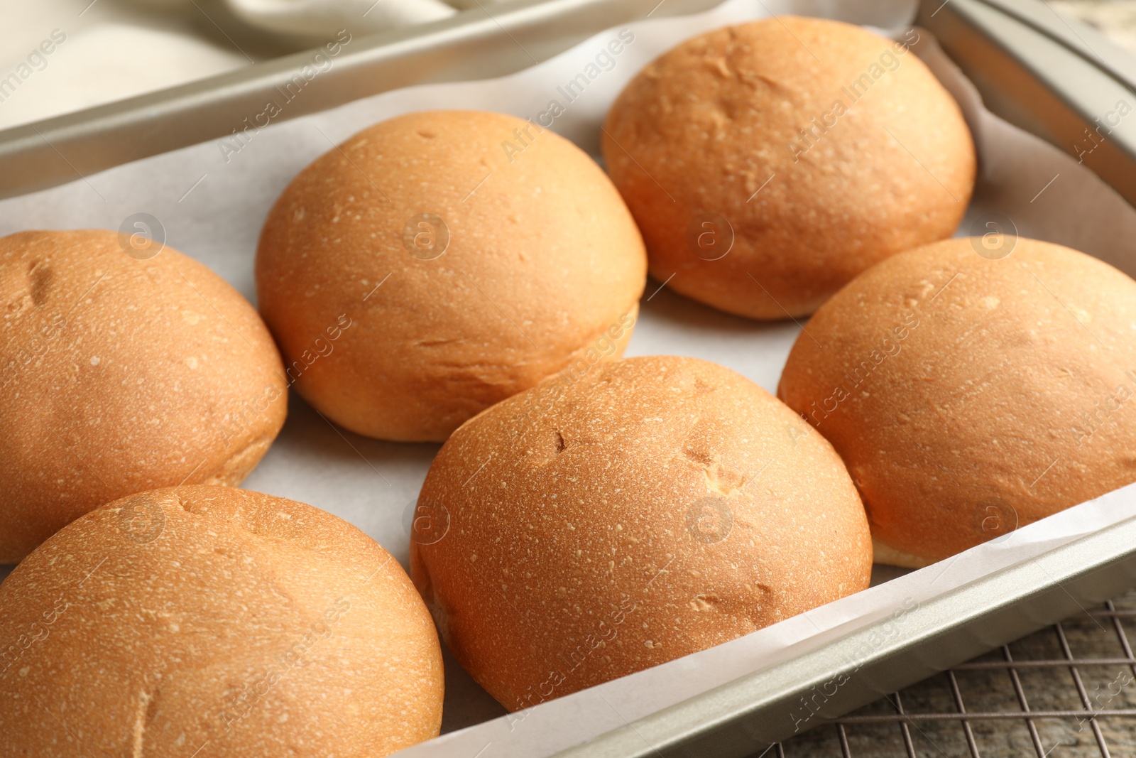 Photo of Fresh tasty buns in baking dish on table, closeup