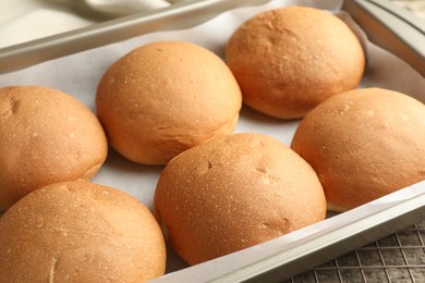 Photo of Fresh tasty buns in baking dish on table, closeup