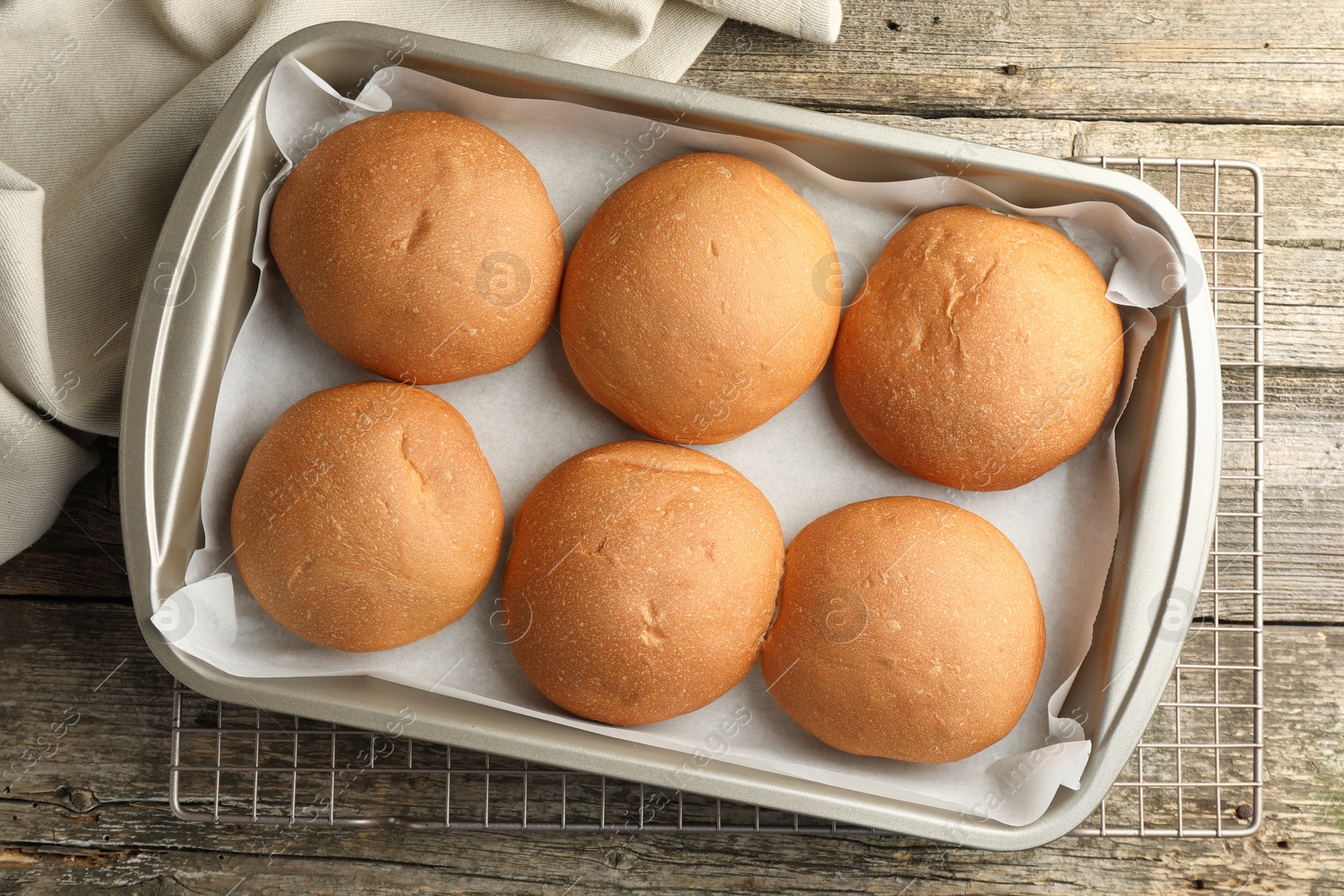 Photo of Fresh tasty buns in baking dish on wooden table, top view