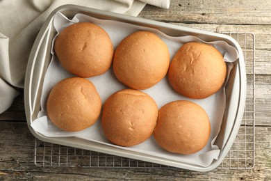 Fresh tasty buns in baking dish on wooden table, top view