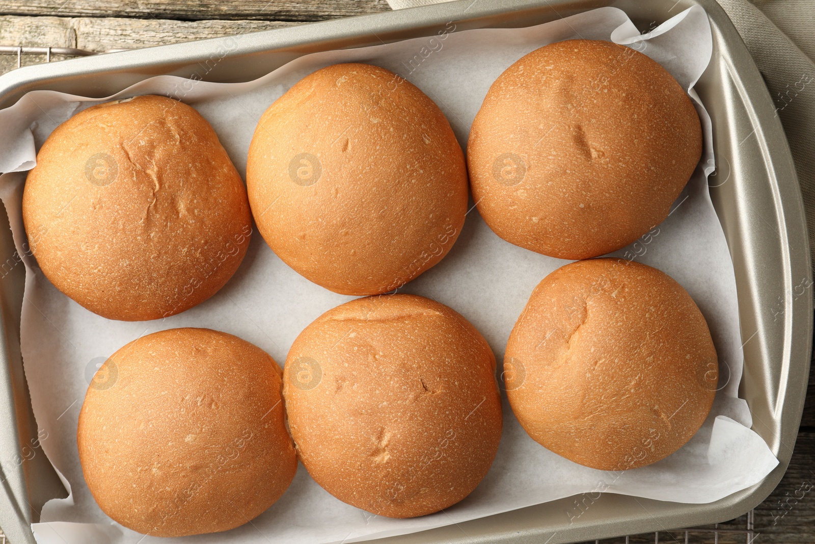 Photo of Fresh tasty buns in baking dish on table, top view