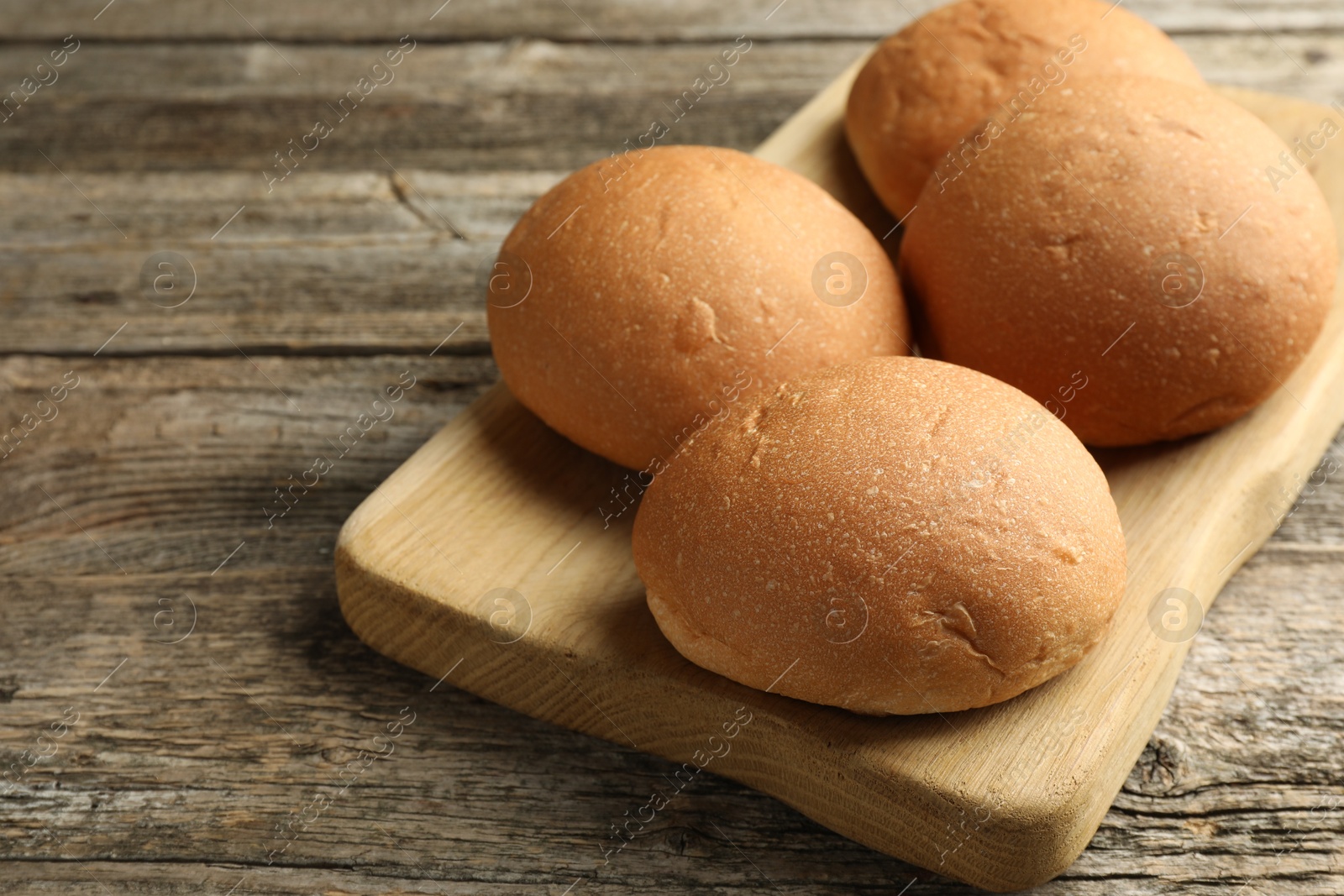 Photo of Fresh tasty buns on wooden table, closeup