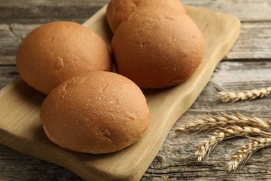 Photo of Fresh tasty buns and spikes on wooden table, closeup