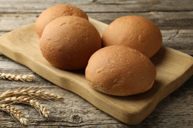 Fresh tasty buns and spikes on wooden table, closeup