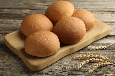 Photo of Fresh tasty buns and spikes on wooden table, closeup