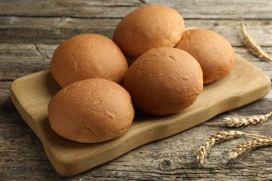 Fresh tasty buns and spikes on wooden table, closeup