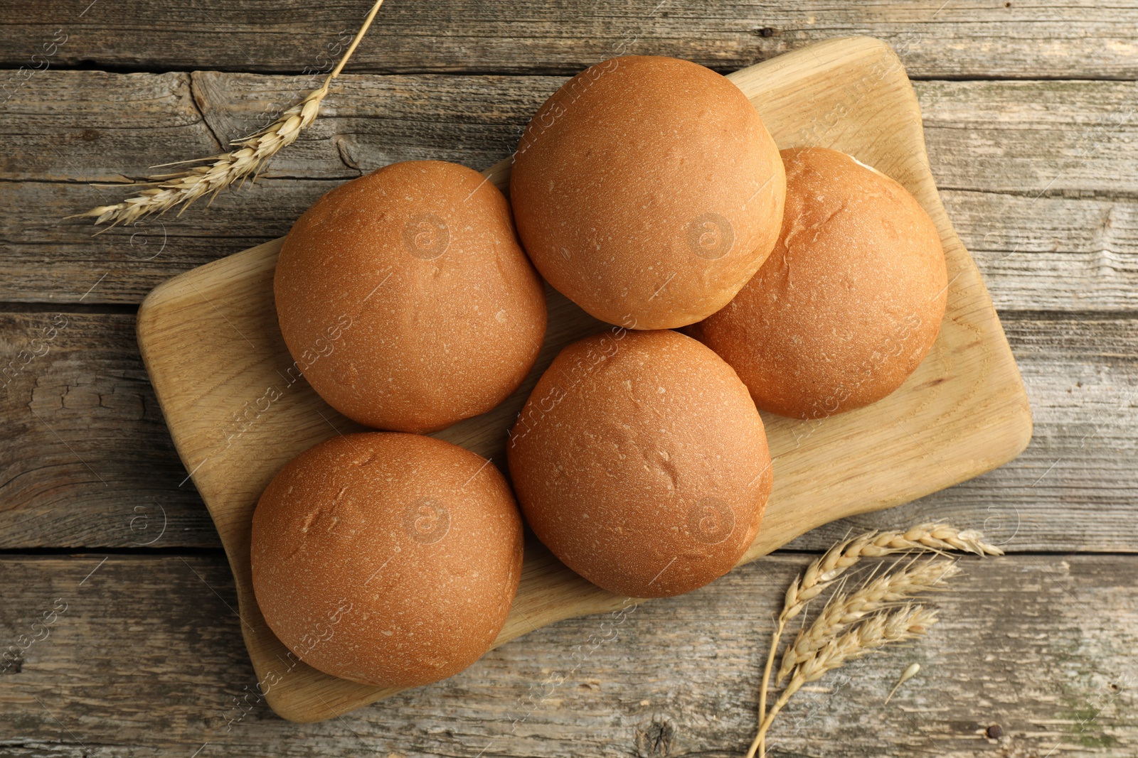 Photo of Fresh tasty buns and spikes on wooden table, top view