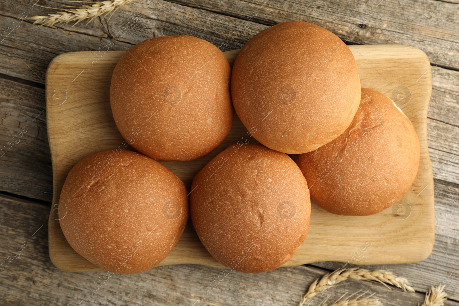 Photo of Fresh tasty buns and spikes on wooden table, top view