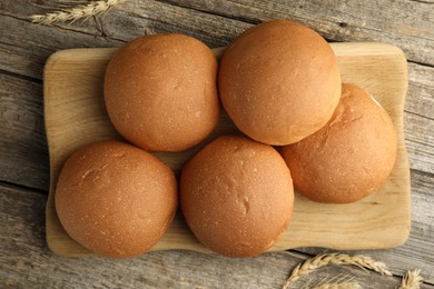 Fresh tasty buns and spikes on wooden table, top view