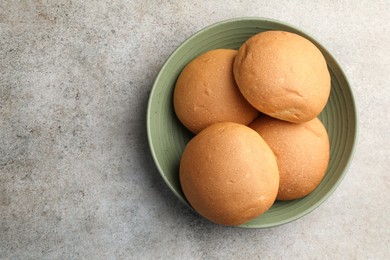 Photo of Fresh tasty buns on grey table, top view. Space for text