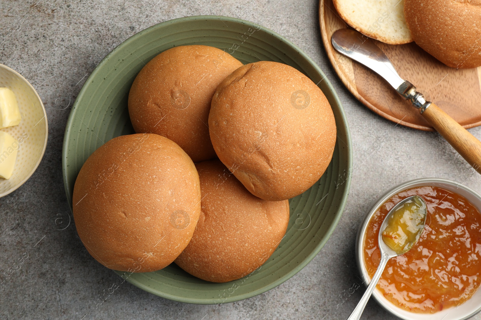 Photo of Fresh tasty buns and jam on grey table, top view