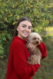 Smiling woman with cute dog in autumn park