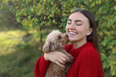 Photo of Smiling woman with cute dog in autumn park. Space for text