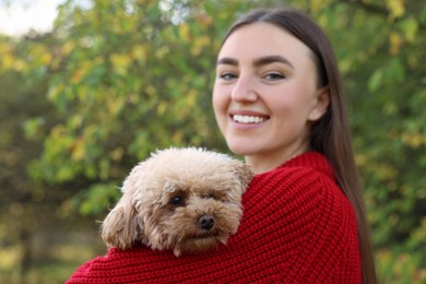 Smiling woman with cute dog in autumn park