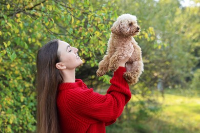 Smiling woman with cute dog in autumn park