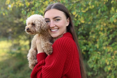 Smiling woman with cute dog in autumn park