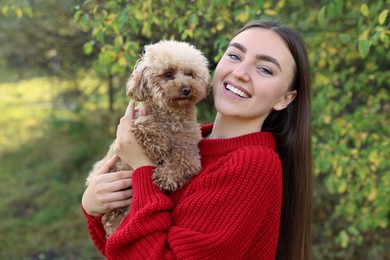 Smiling woman with cute dog in autumn park