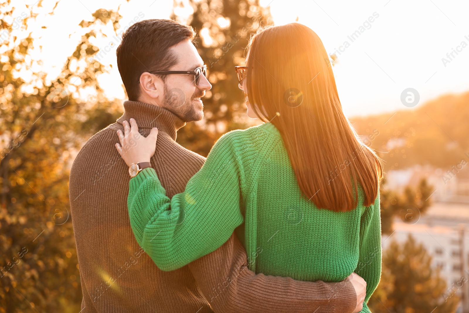 Photo of Cute couple enjoying autumn evening outdoors together, back view