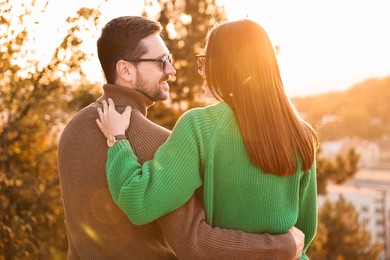 Photo of Cute couple enjoying autumn evening outdoors together, back view