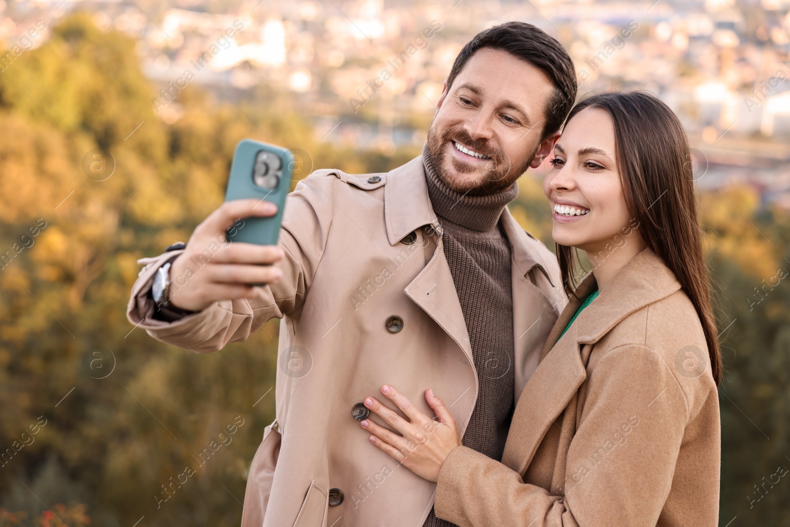 Photo of Beautiful couple taking selfie together outdoors on autumn day