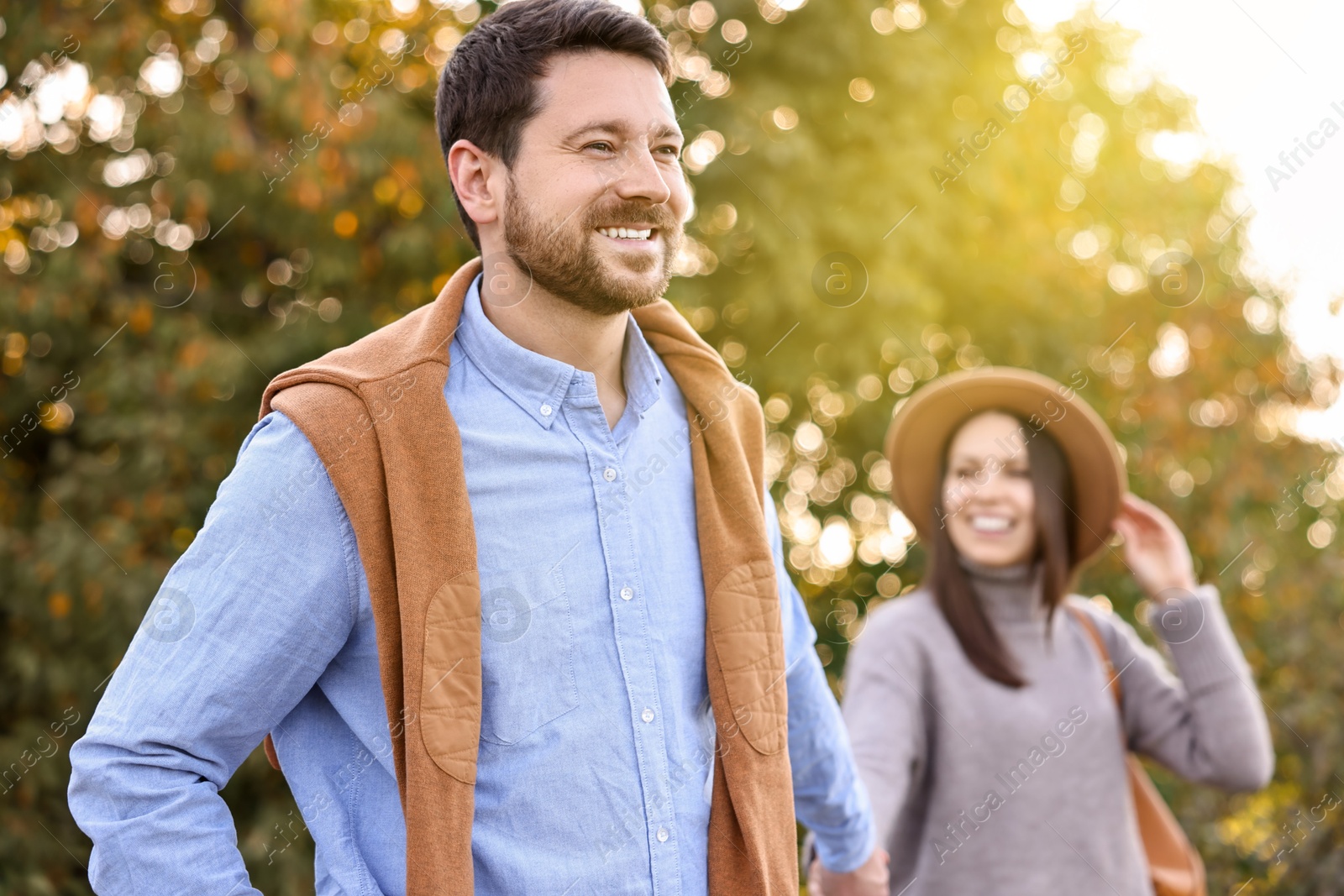 Photo of Beautiful couple walking together in park on autumn day, selective focus