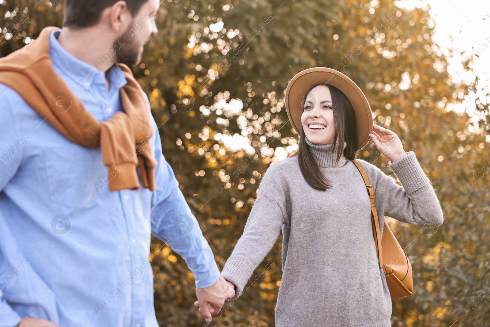 Photo of Beautiful couple walking together in park on autumn day, selective focus