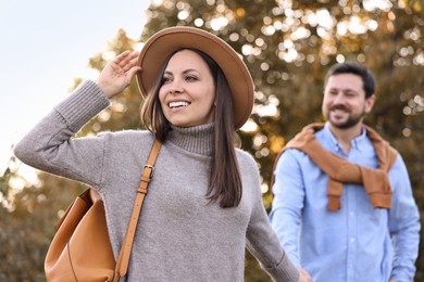 Beautiful couple walking together in park on autumn day, selective focus