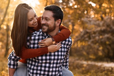 Photo of Beautiful couple having fun together in park on autumn day, space for text