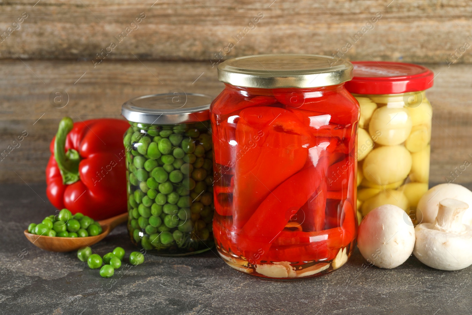 Photo of Different pickled products in jars on grey textured table