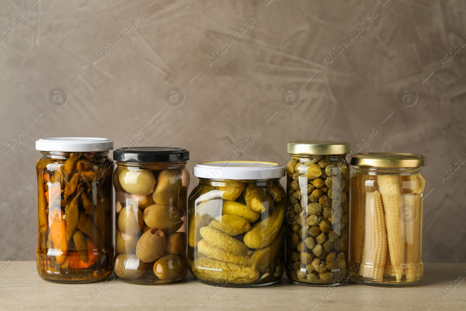 Photo of Different pickled products in jars on wooden table