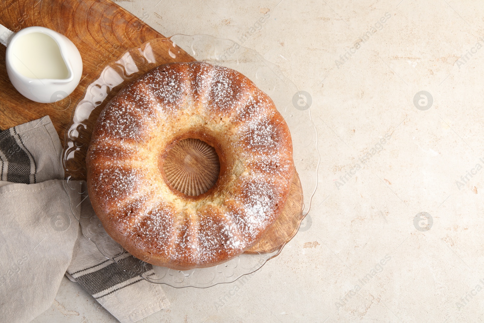 Photo of Freshly baked sponge cake and milk on light grey table, top view. Space for text