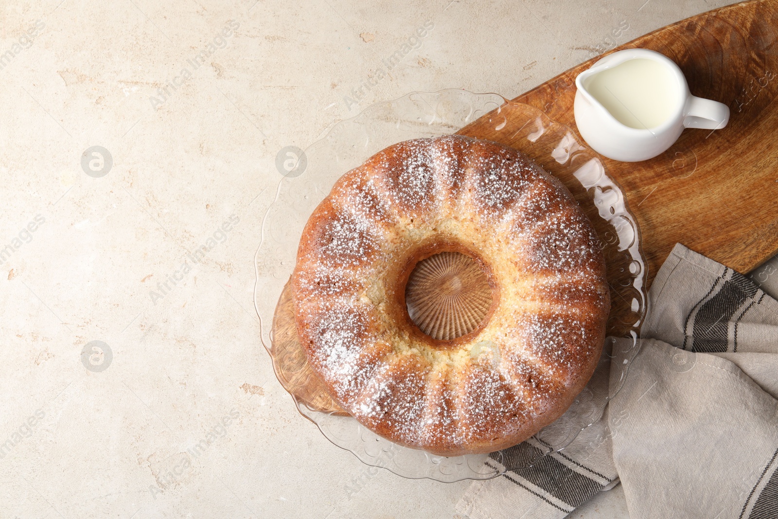 Photo of Freshly baked sponge cake and milk on light grey table, top view. Space for text