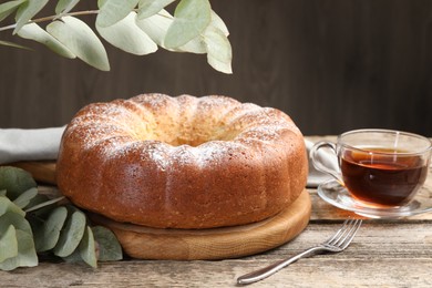 Freshly baked sponge cake, tea and eucalyptus leaves on wooden table