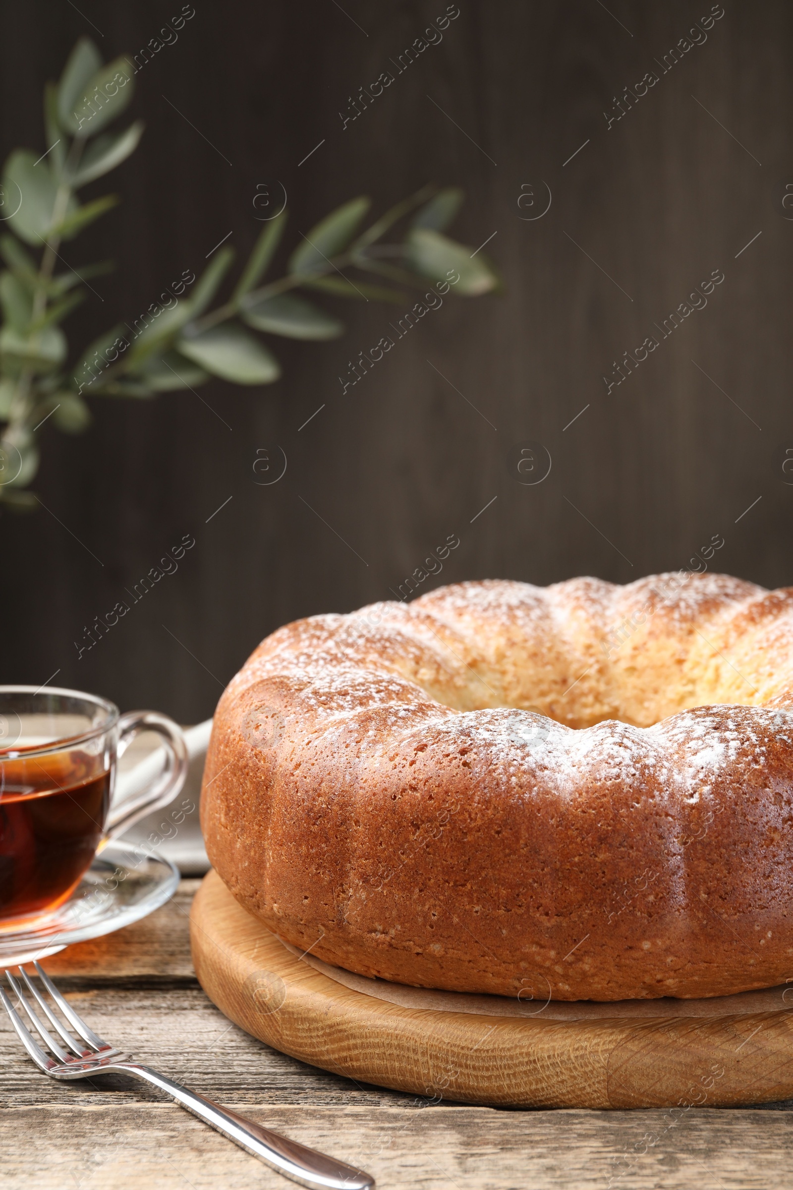 Photo of Freshly baked sponge cake and tea on wooden table, closeup