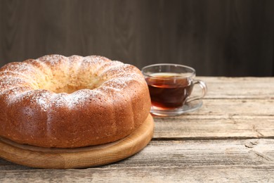 Photo of Freshly baked sponge cake and tea on wooden table, closeup