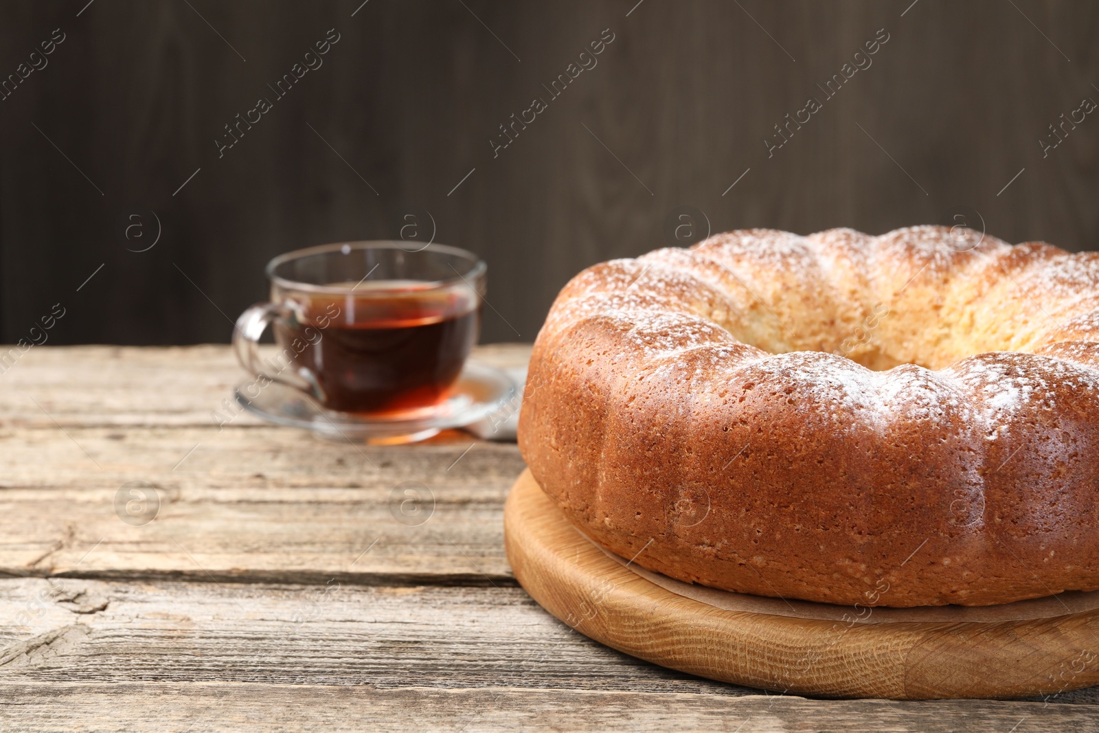 Photo of Freshly baked sponge cake and tea on wooden table, closeup